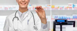 Woman smiling while holding supplement capsule