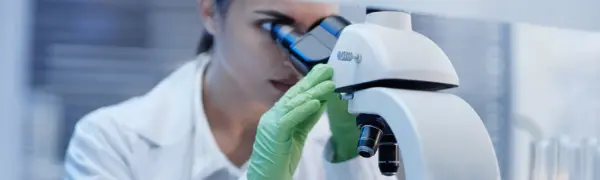 Young adult caucasian woman observing specimen through laboratory microscope